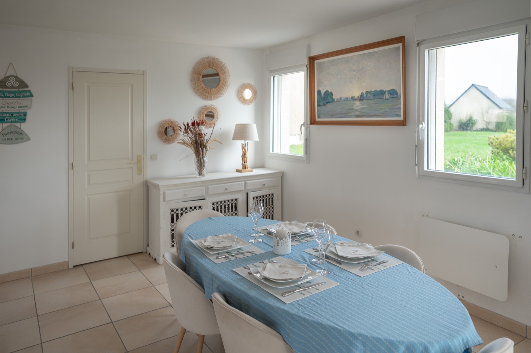 Salle à manger avec grande table dressée et buffet blanc